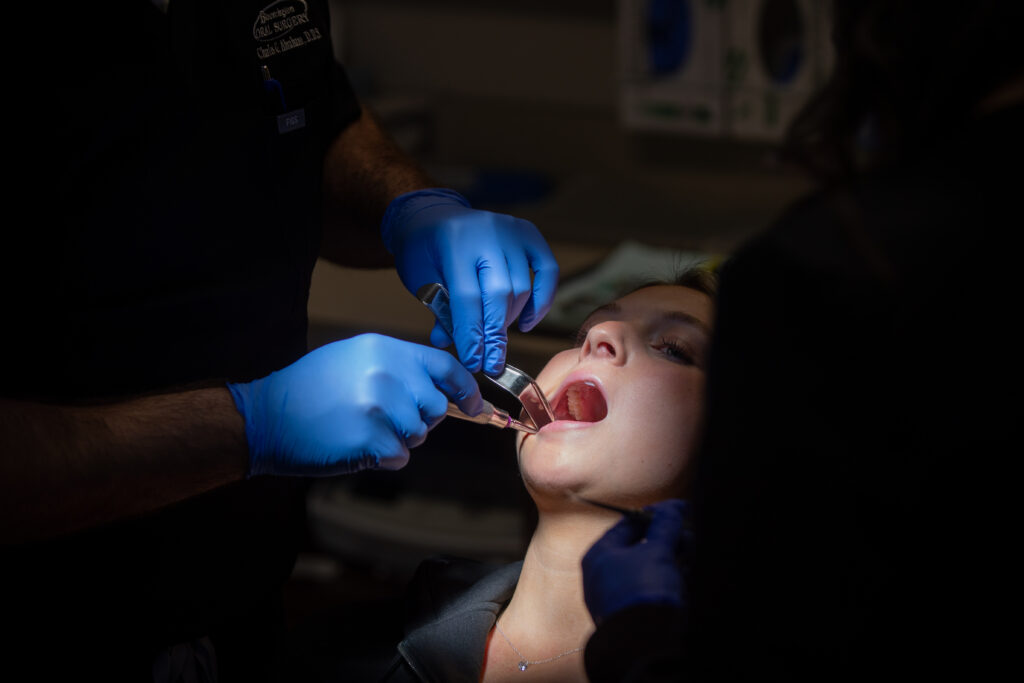 oral surgery patient with tools in her open mouth