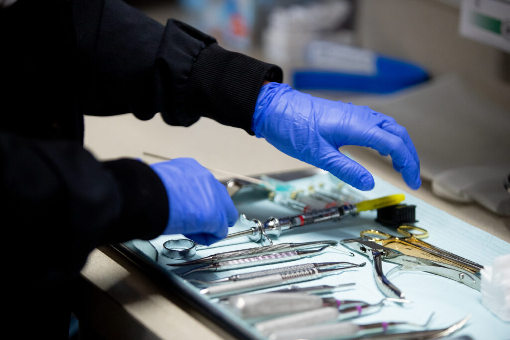 gloved hands preparing tools for a procedure at Washington Oral & Facial Surgery