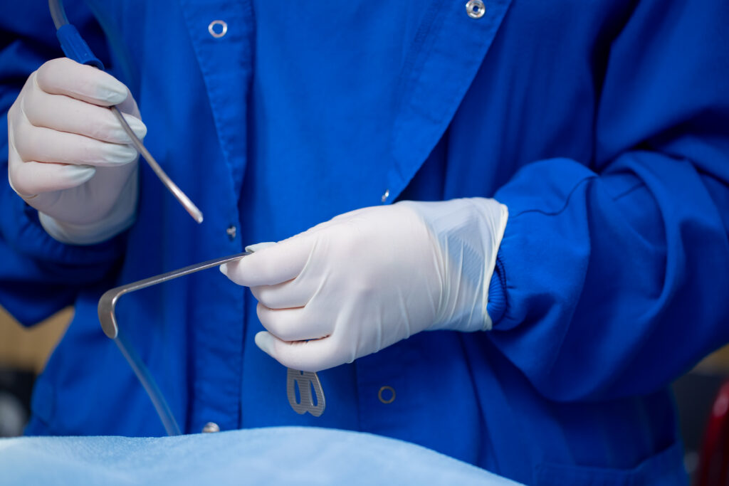 gloved hands holding surgical tools