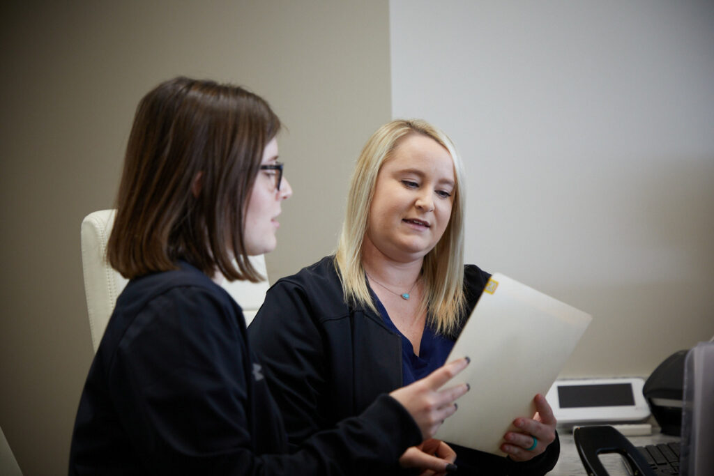 two female administrative personnel looking at a file at Washington Oral & Facial Surgery