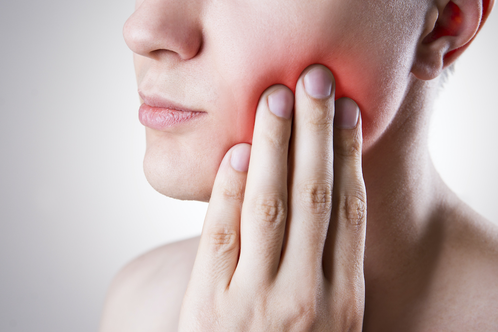 woman holding her red painful cheek