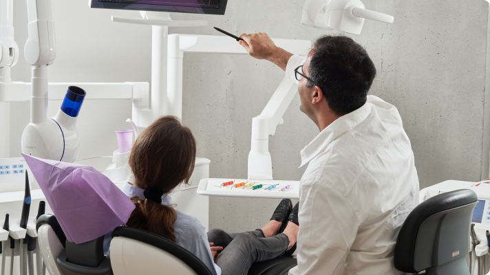 surgeon pointing at a screen explaining pre-operative instructions to a patient