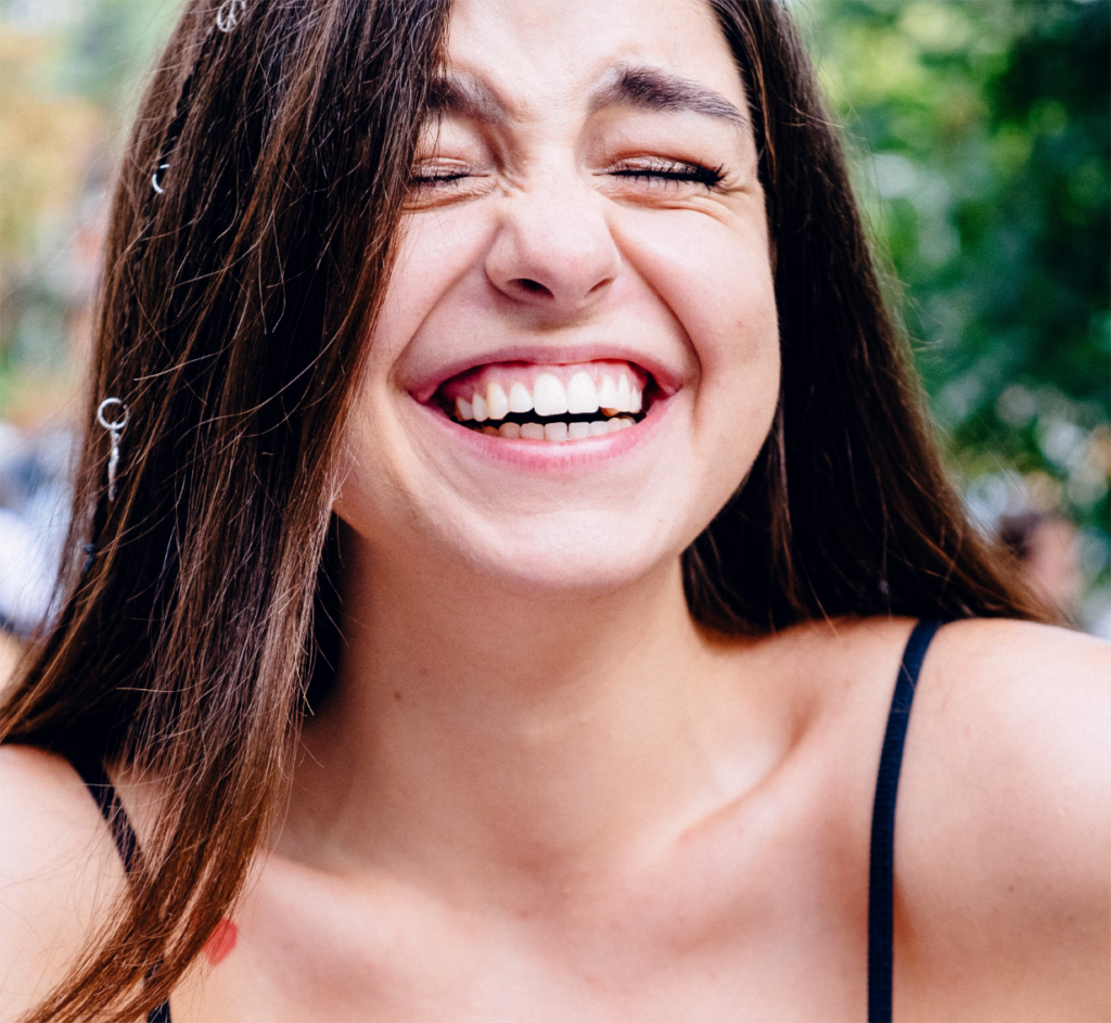 young woman smiling and laughing showing her beautiful teeth and smile